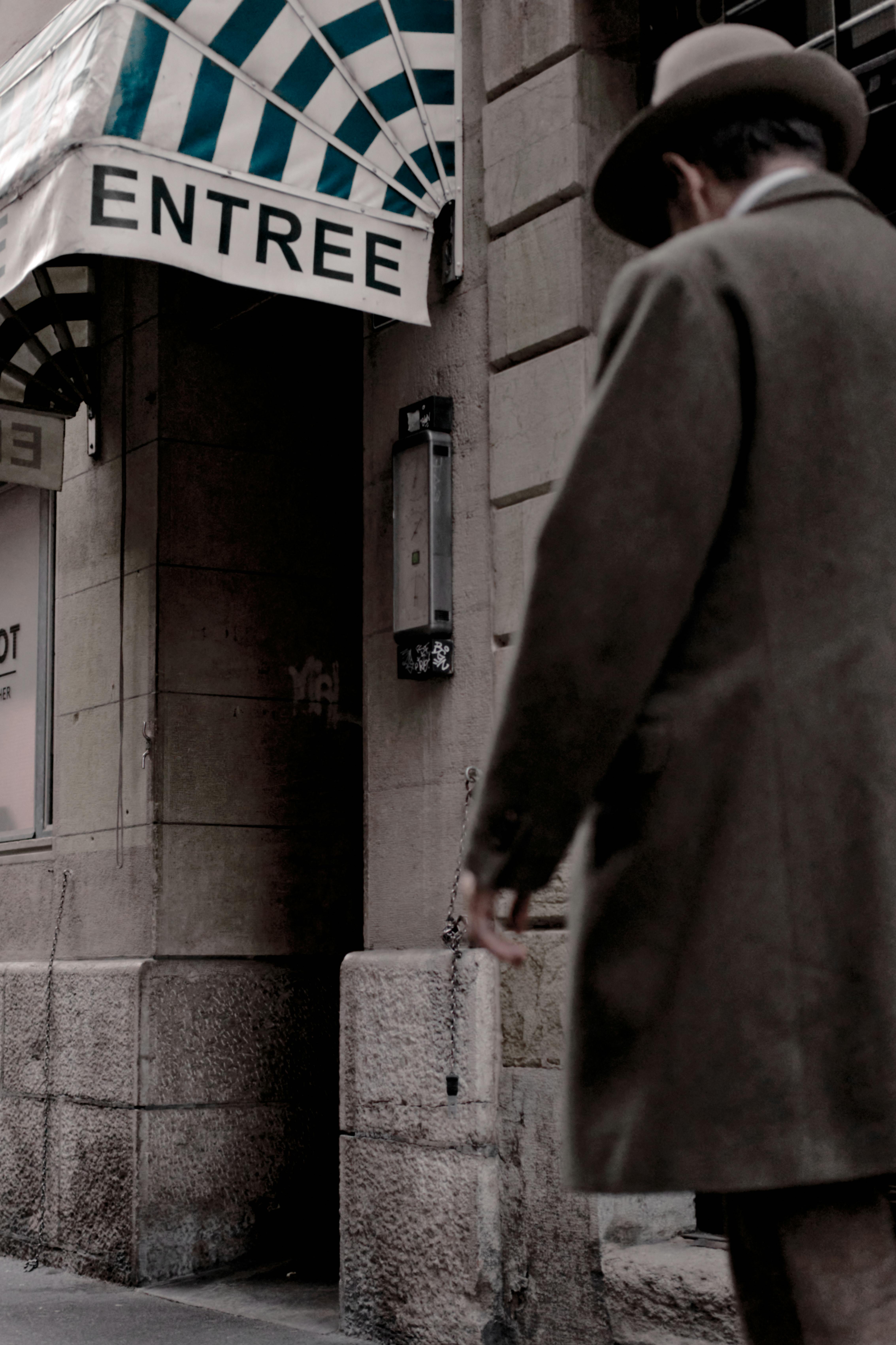 Kostenlos Ein Herr geht in der Nähe des Eingangs eines historischen Gebäudes in Neuchâtel, Schweiz, spazieren. Stock-Foto