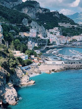 A breathtaking aerial view of the Amalfi coastline with vibrant cliffs and a busy marina under a clear blue sky.