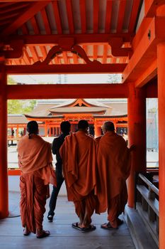 Buddhist monks exploring a vibrant red Japanese temple
