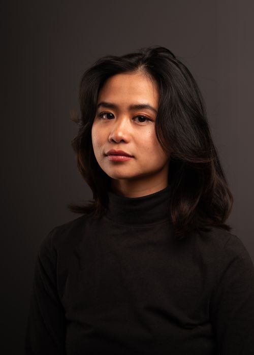 Free A close-up portrait of a woman with dark hair wearing a black turtleneck against a dark background. Stock Photo