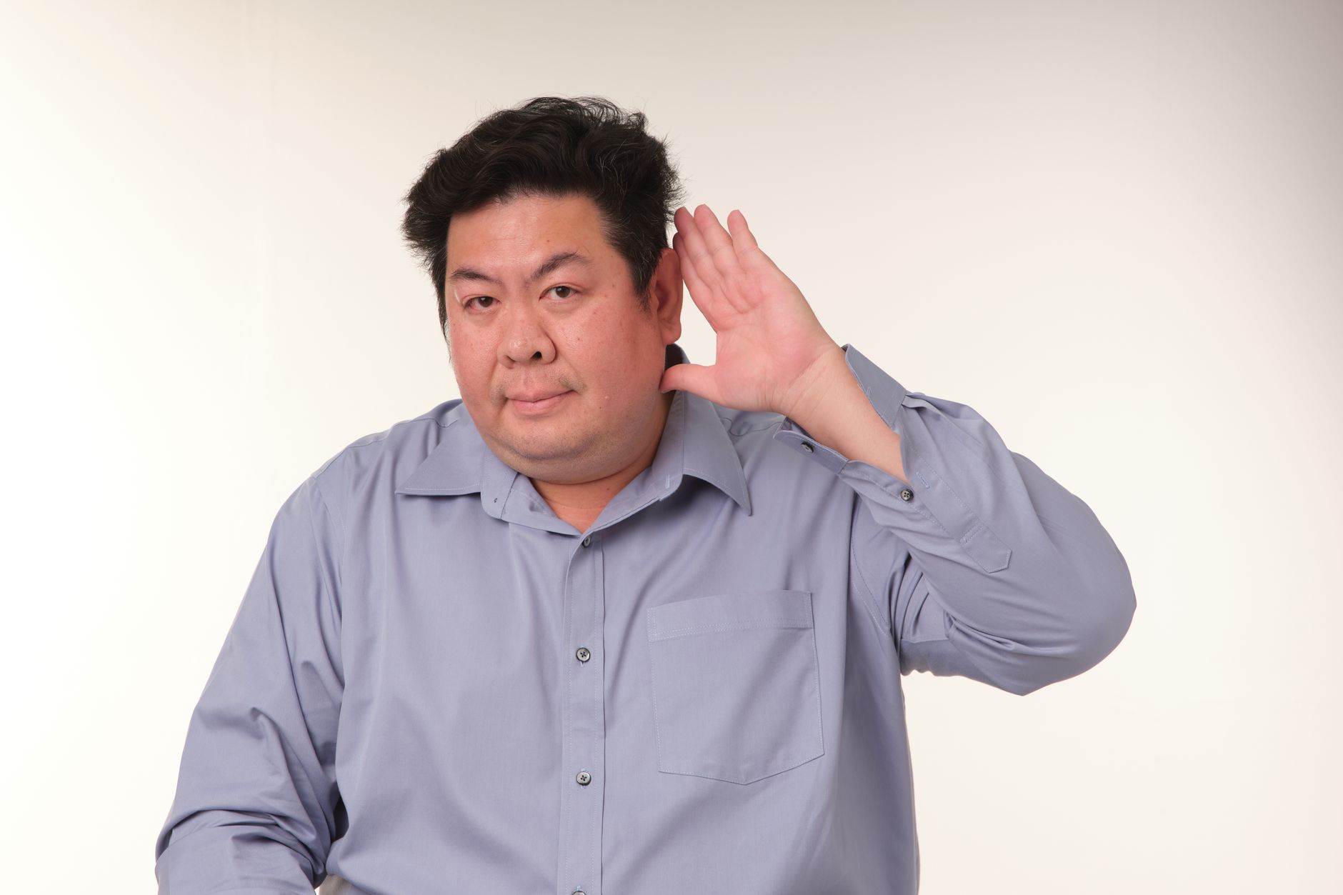 A man in a pose demonstrating the gesture of listening in a studio setting.