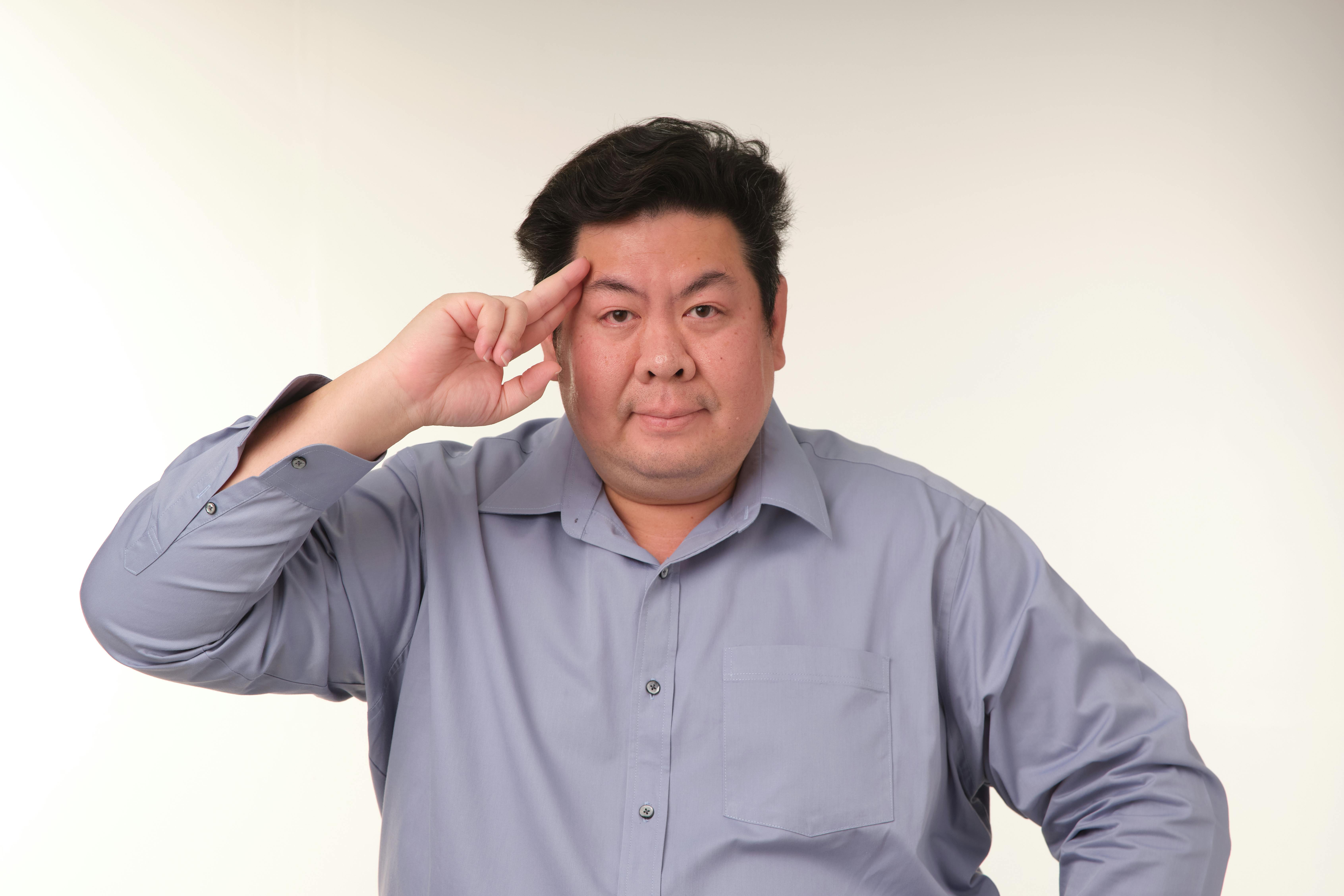 무료 회색 셔츠를 입고 경례하는 중년 아시아 남성의 초상화. 스톡 사진