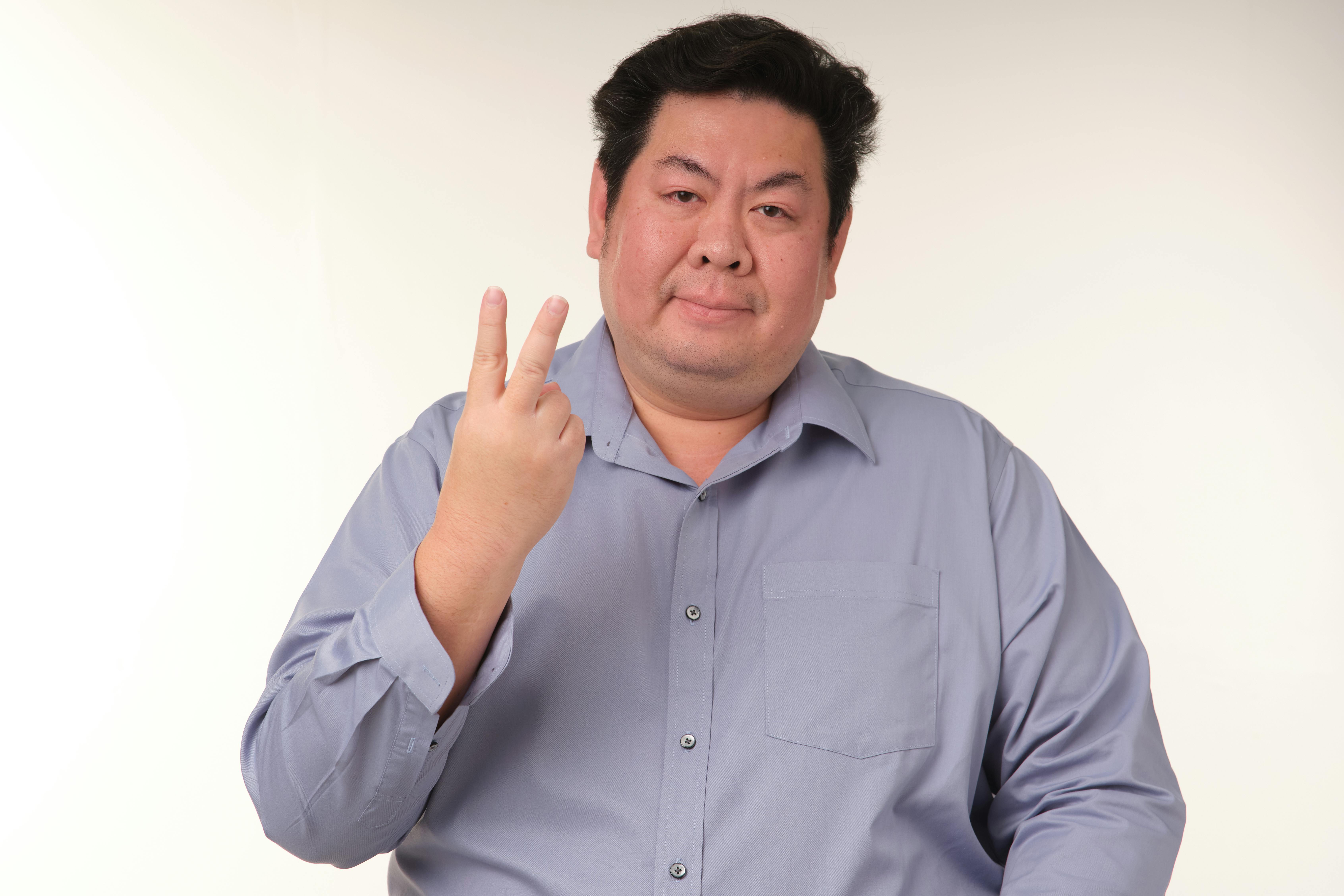 Kostenlos Porträt eines lächelnden erwachsenen Mannes in einem blauen Hemd, der ein Peace-Zeichen macht. Stock-Foto