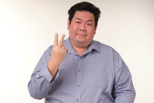 Free Portrait of a smiling adult man in a blue shirt making a peace sign gesture. Stock Photo