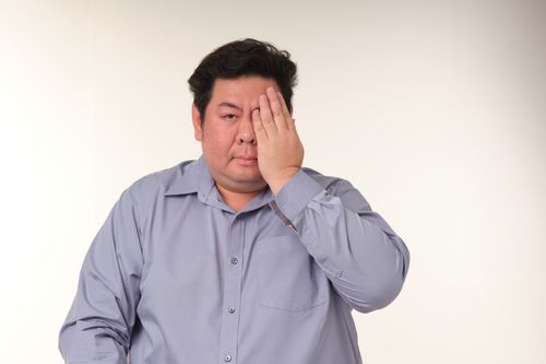 Free Man in a blue shirt covering one eye with hand, isolated background. Stock Photo