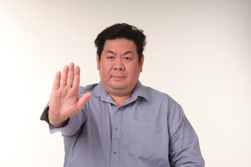 Free Portrait of a man in blue shirt gesturing stop with hand, studio background. Stock Photo