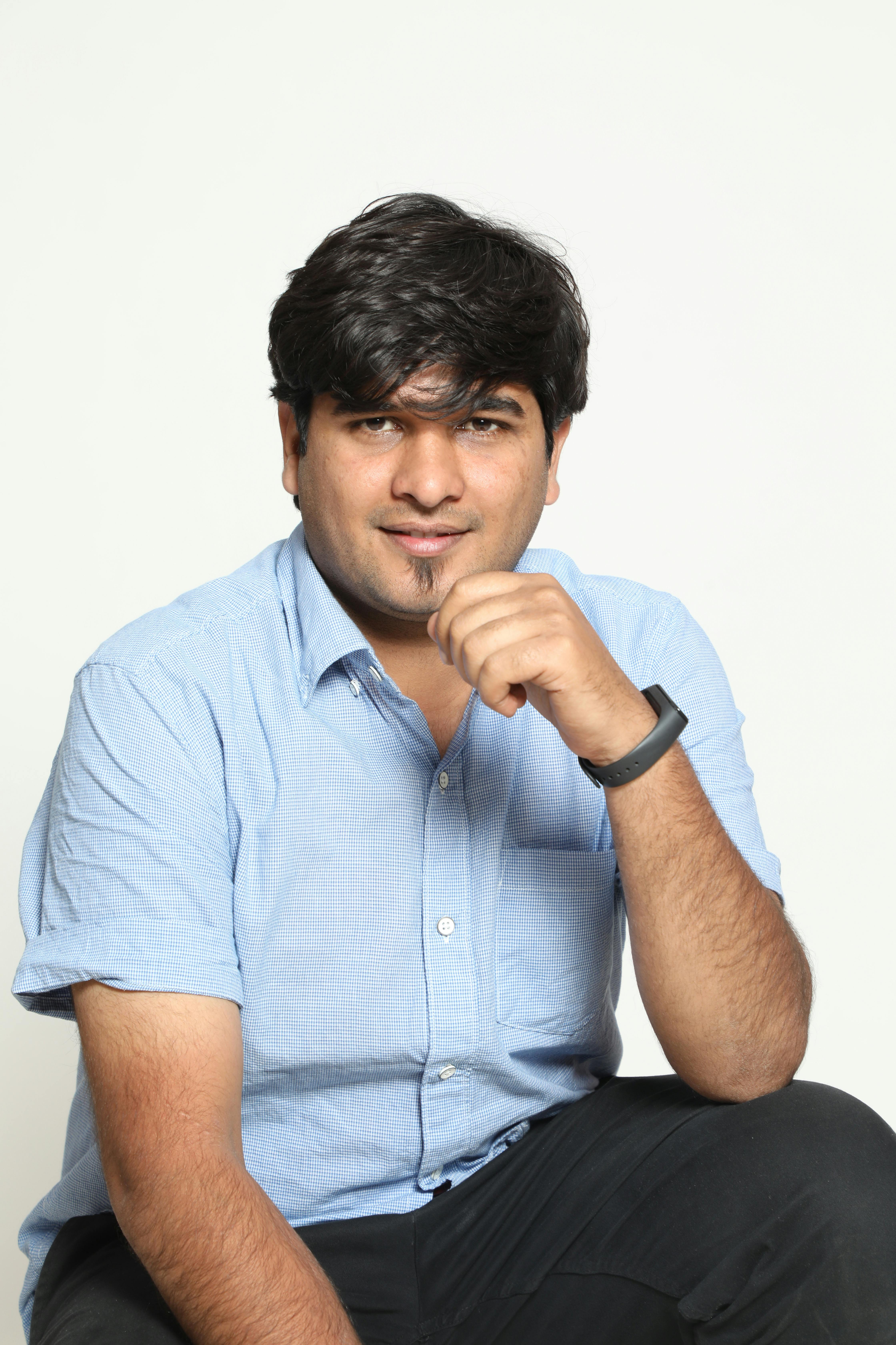 Portrait of a confident young man seated in a studio setting with a thoughtful expression.