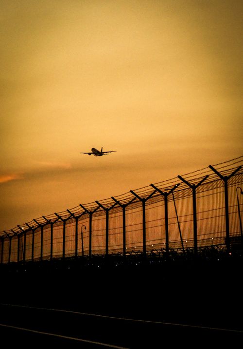 Free Silhouette of a plane taking off at sunset with airport fence in Jakarta. Dramatic sky creates a striking scene. Stock Photo
