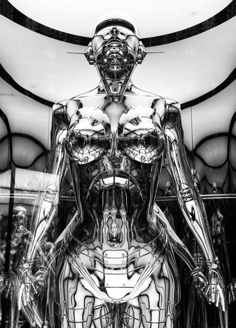 Black and white image of a futuristic chrome robot with a humanoid design in an abstract setting.