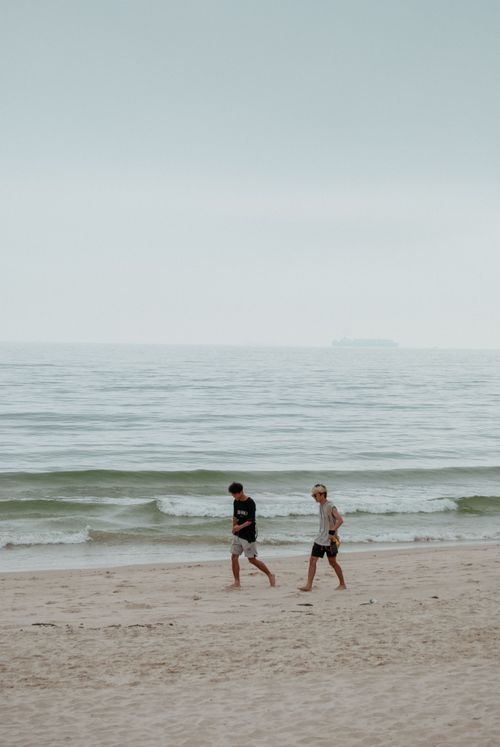 Free Two adults walking along a calm beach, enjoying a peaceful day by the sea. Stock Photo