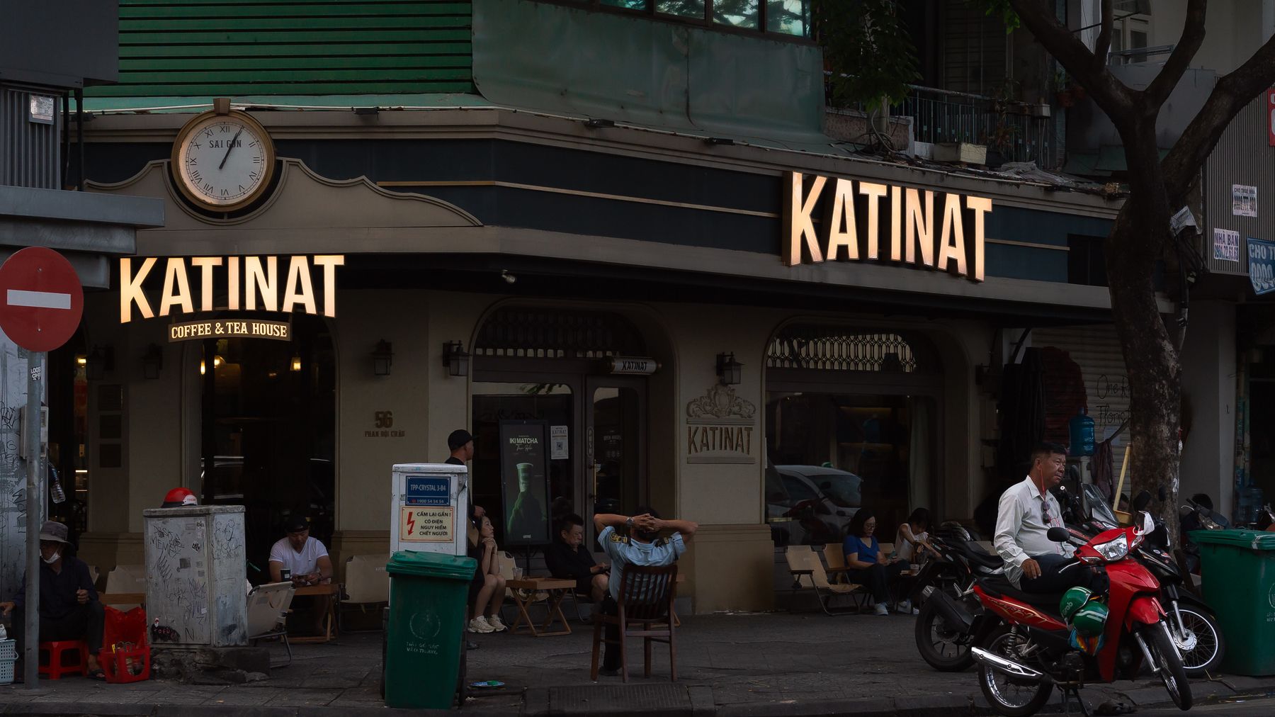 A city street view featuring Katinat Coffee & Tea House with patrons outside.