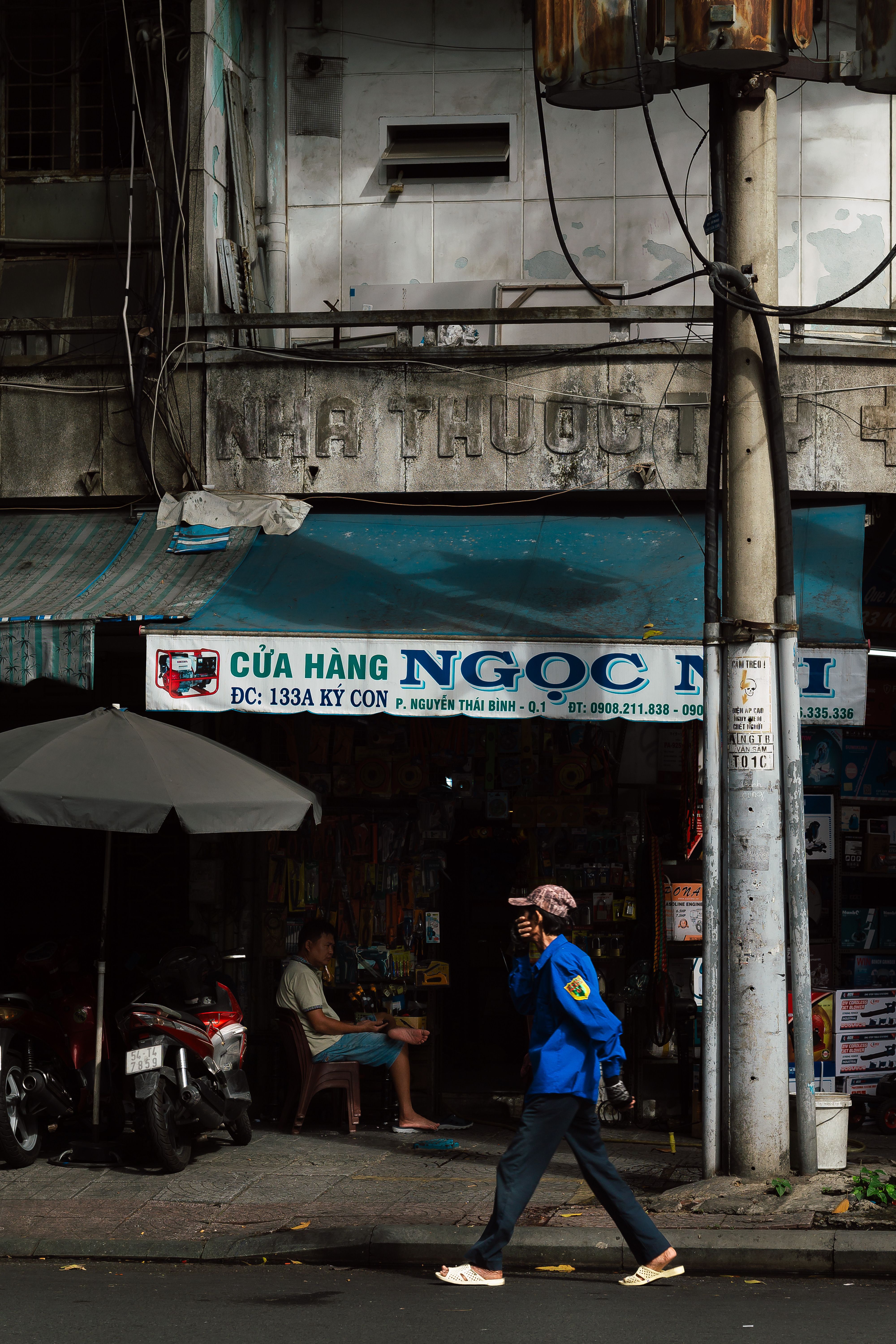 A man walking past a shop in an urban street in Vietnam.