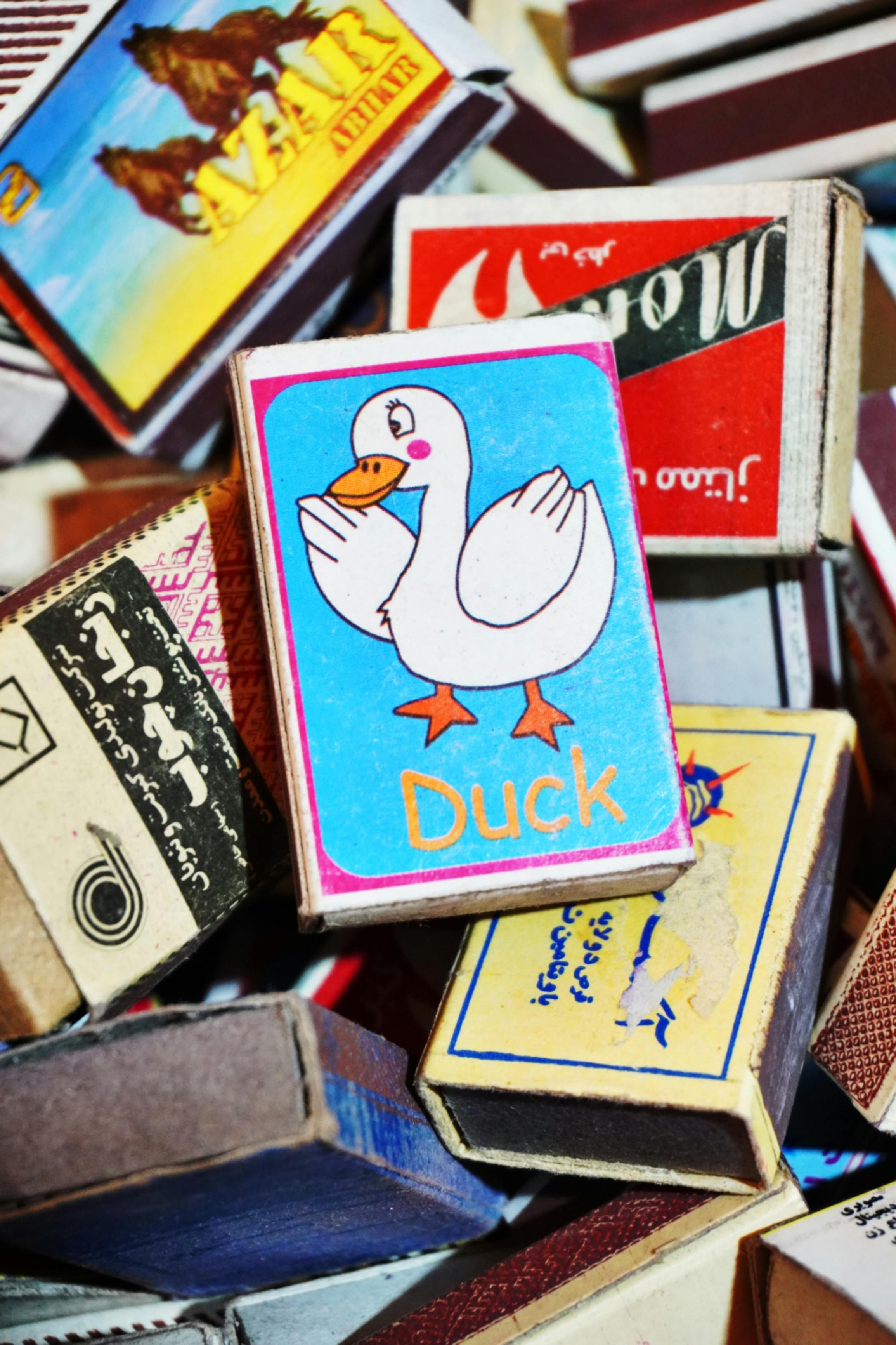 A vibrant assortment of matchboxes featuring a playful duck illustration on a prominent box.