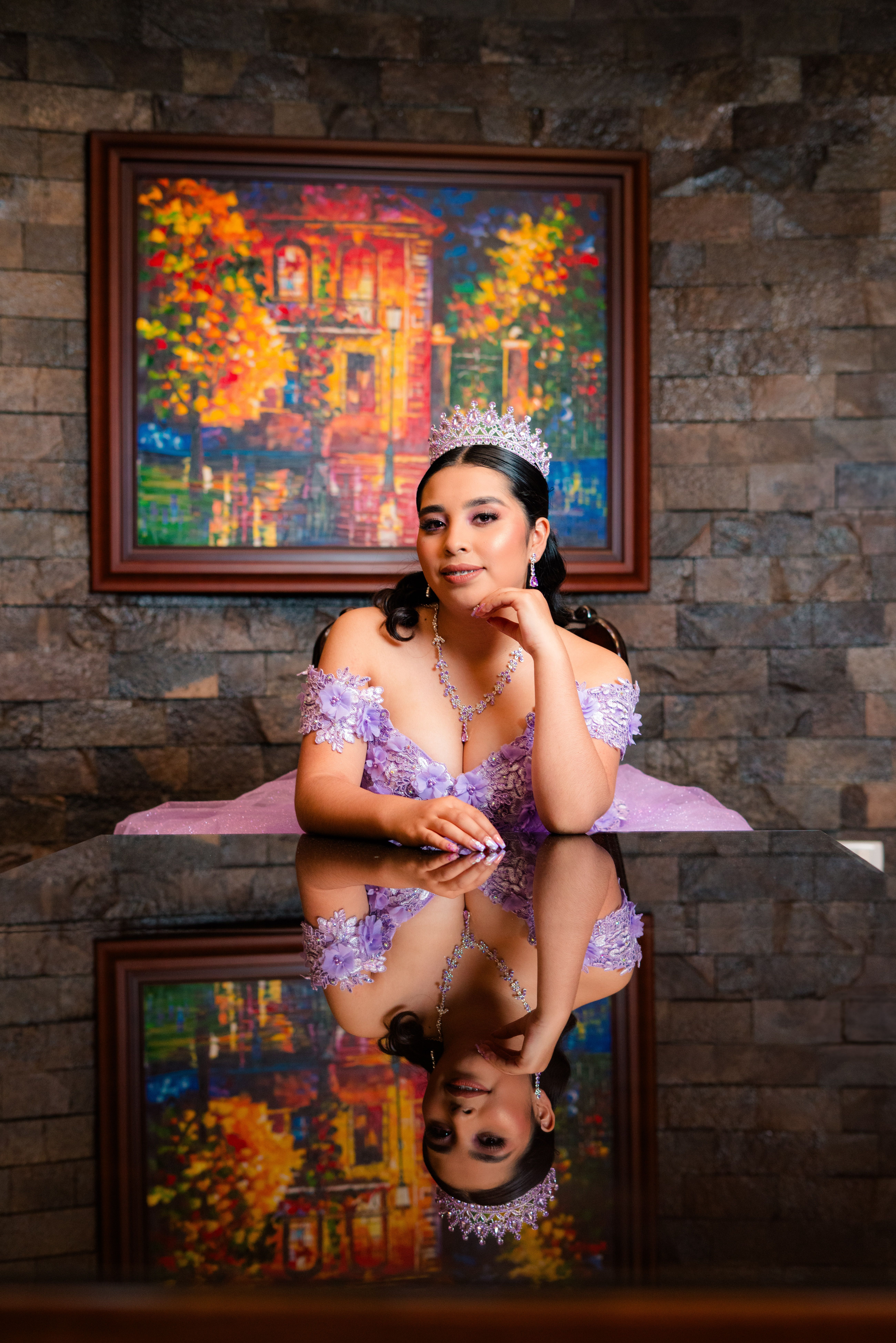 A woman in a lavender dress and tiara reflected on a table indoors.