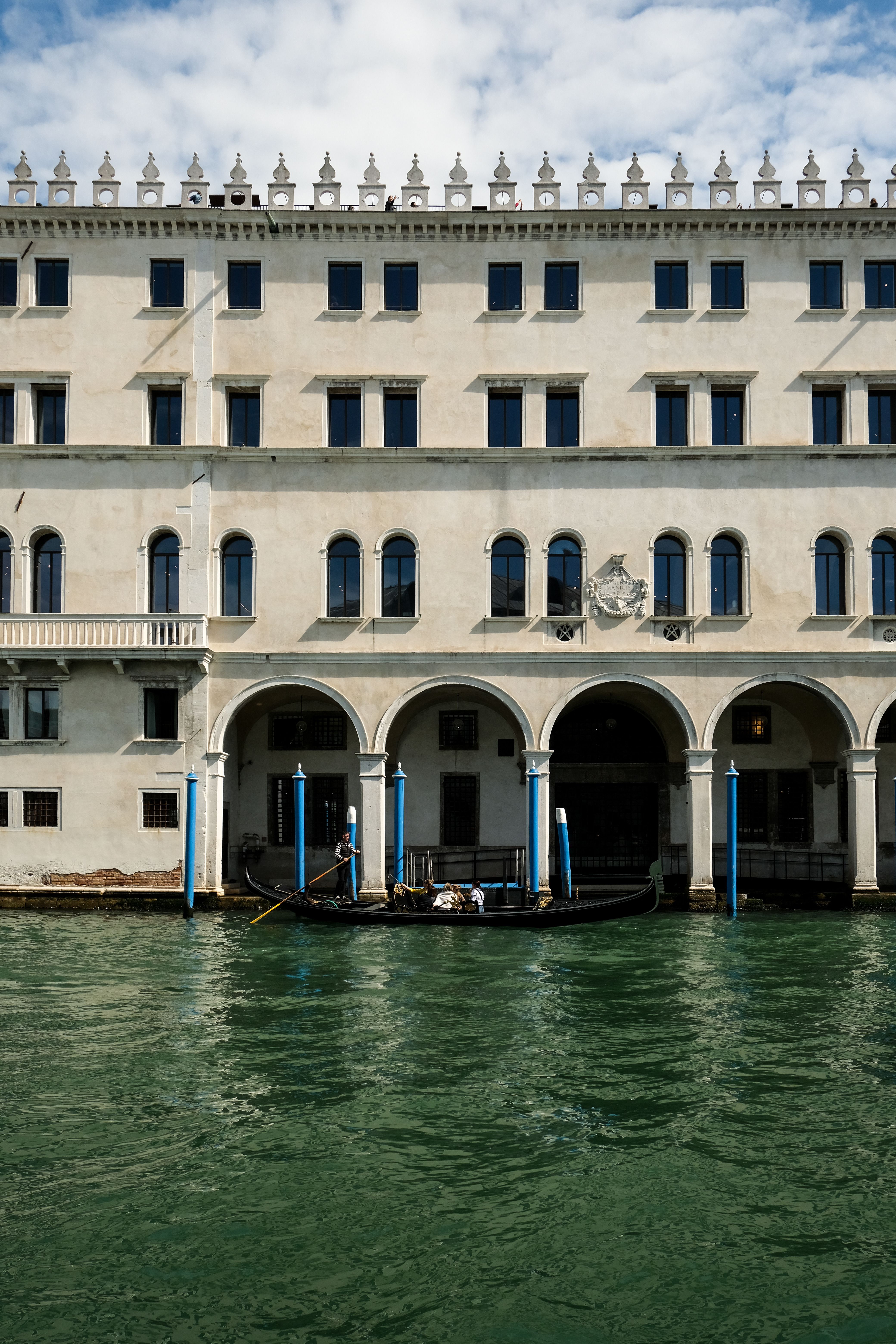 A gondola glides along a Venetian canal beside an ornate historic building.