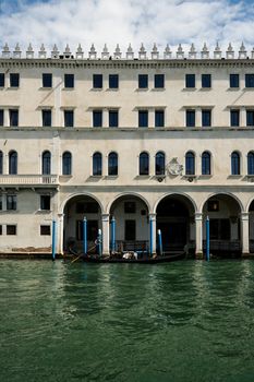 A gondola glides along a Venetian canal beside an ornate historic building.