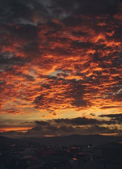 Breathtaking view of a dramatic sunset sky over Cuenca, showcasing vibrant clouds and a scenic urban landscape.