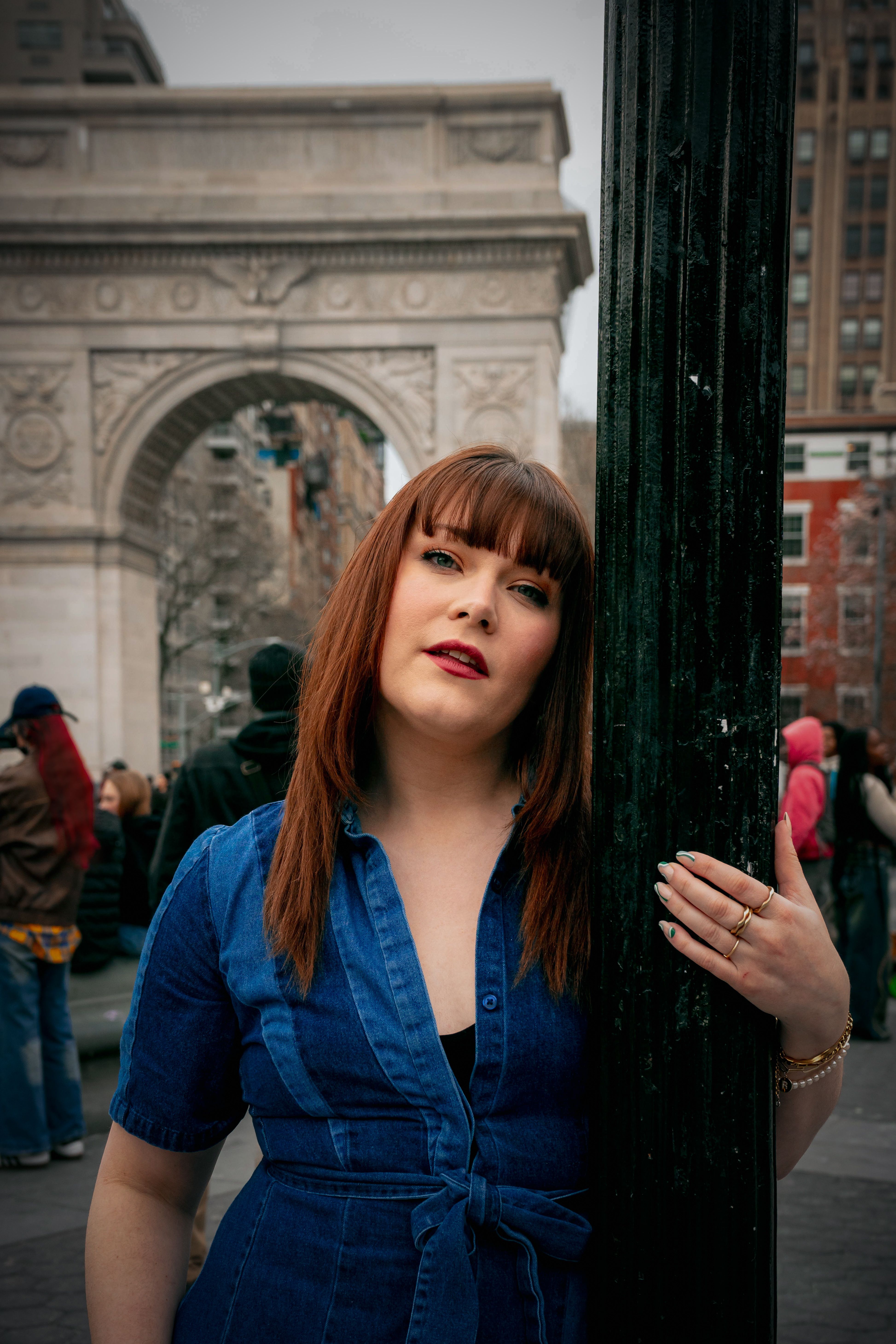 Fashion-forward woman in denim poses at iconic Washington Square Arch in New York City.