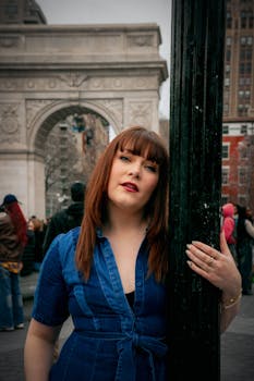 Fashion-forward woman in denim poses at iconic Washington Square Arch in New York City.
