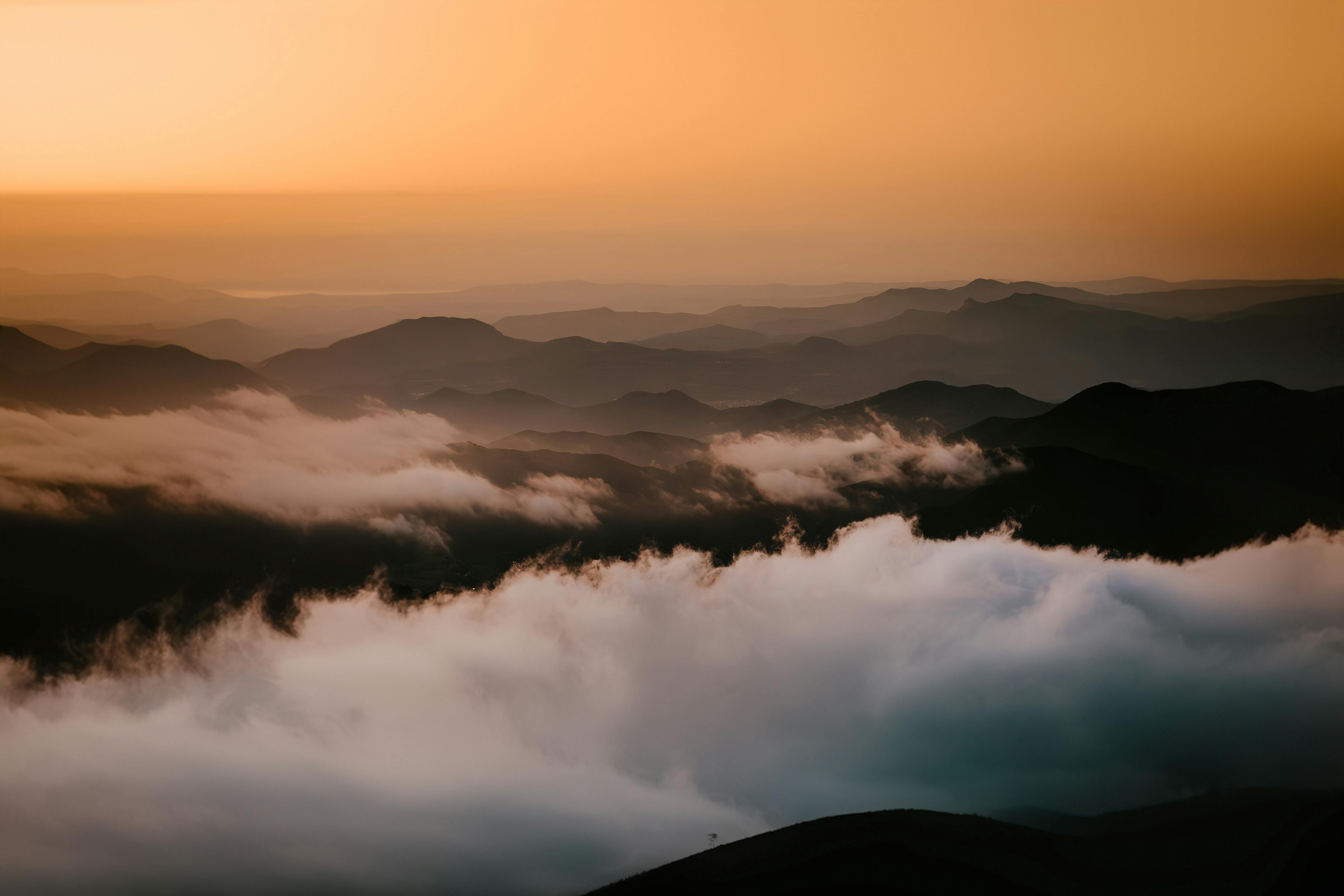 Majestic mountain vistas with clouds and golden sunrise hues.