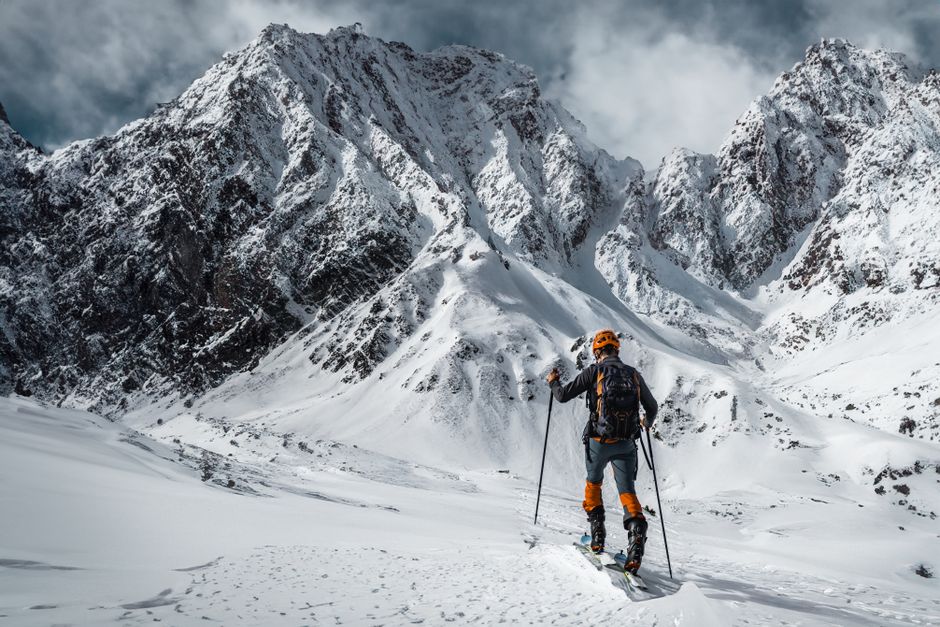 A skier equipped with gear explores a breathtaking snowy mountain landscape.