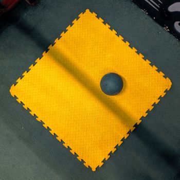 An overhead view of a yellow gym mat with a medicine ball in a gym setting, providing vibrant contrast.