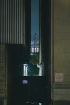 Mysterious nighttime view through a Houston alley revealing a dome in the distance.