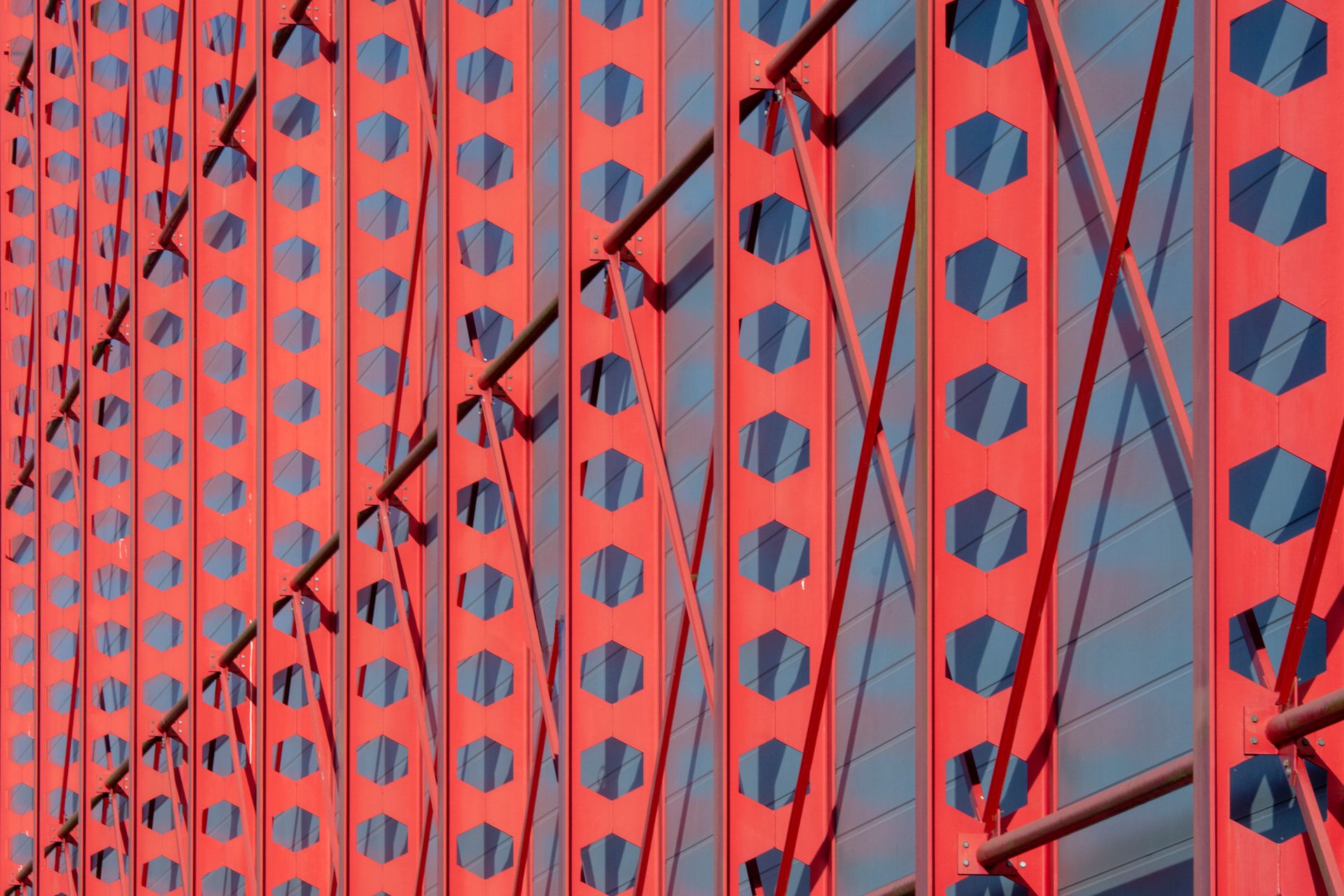 Perspective view of a modern red architectural facade with geometric patterns and shadows.