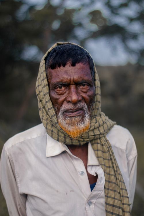 Free Elderly man with a plaid scarf stands outdoors, showcasing a story etched in his eyes. Stock Photo