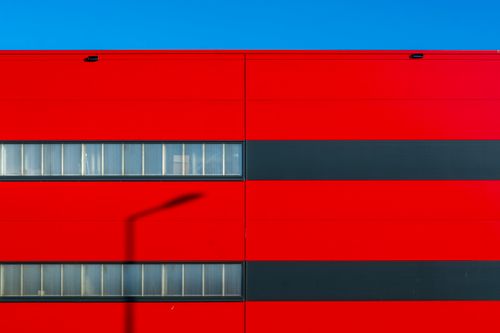 Free Bright red modern building facade with a shadow and clear blue sky, emphasizing minimalism and bold design. Stock Photo