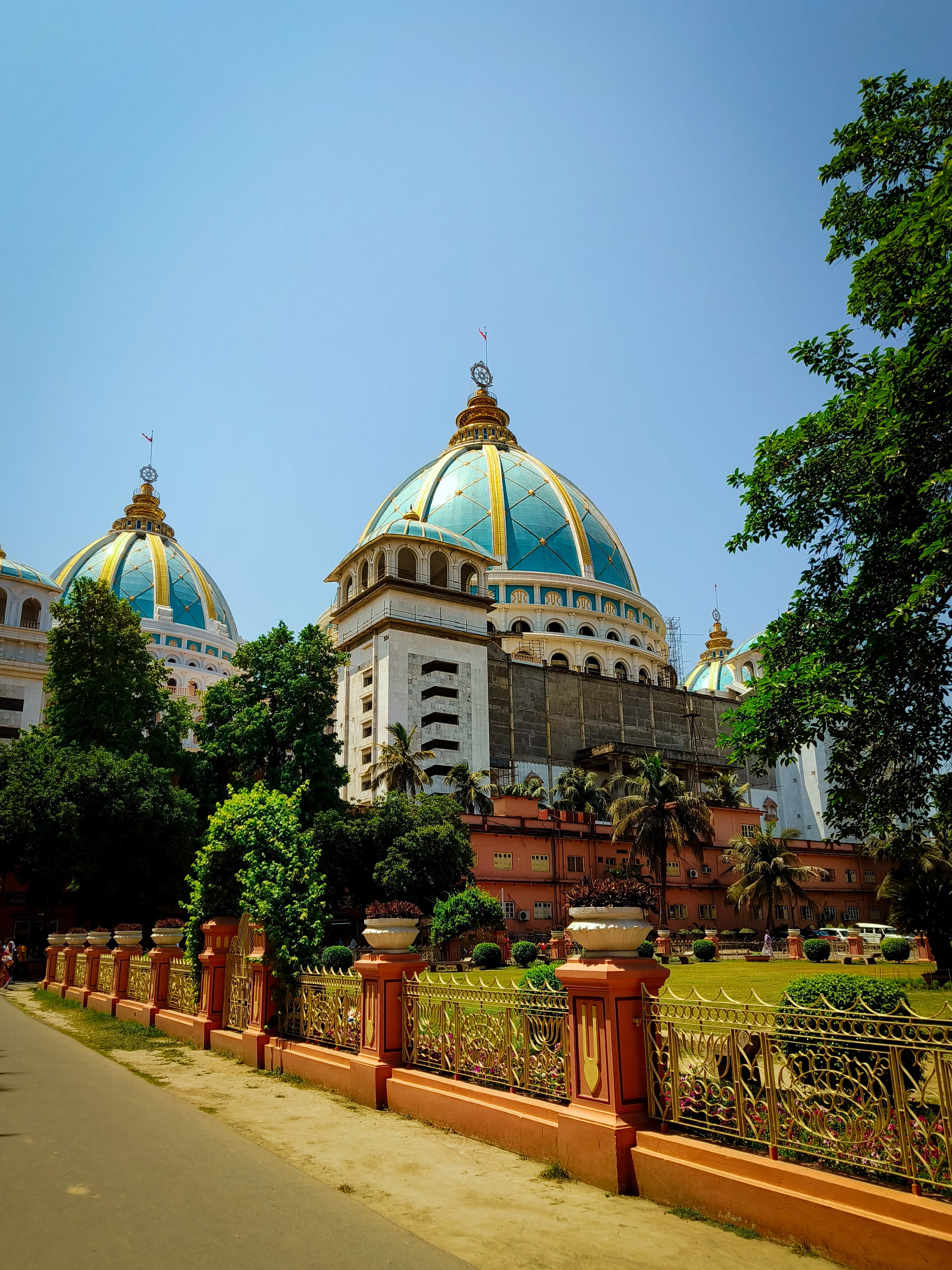 A stunning temple with golden domes and lush greenery under a clear blue sky, showcasing architectural marvel.