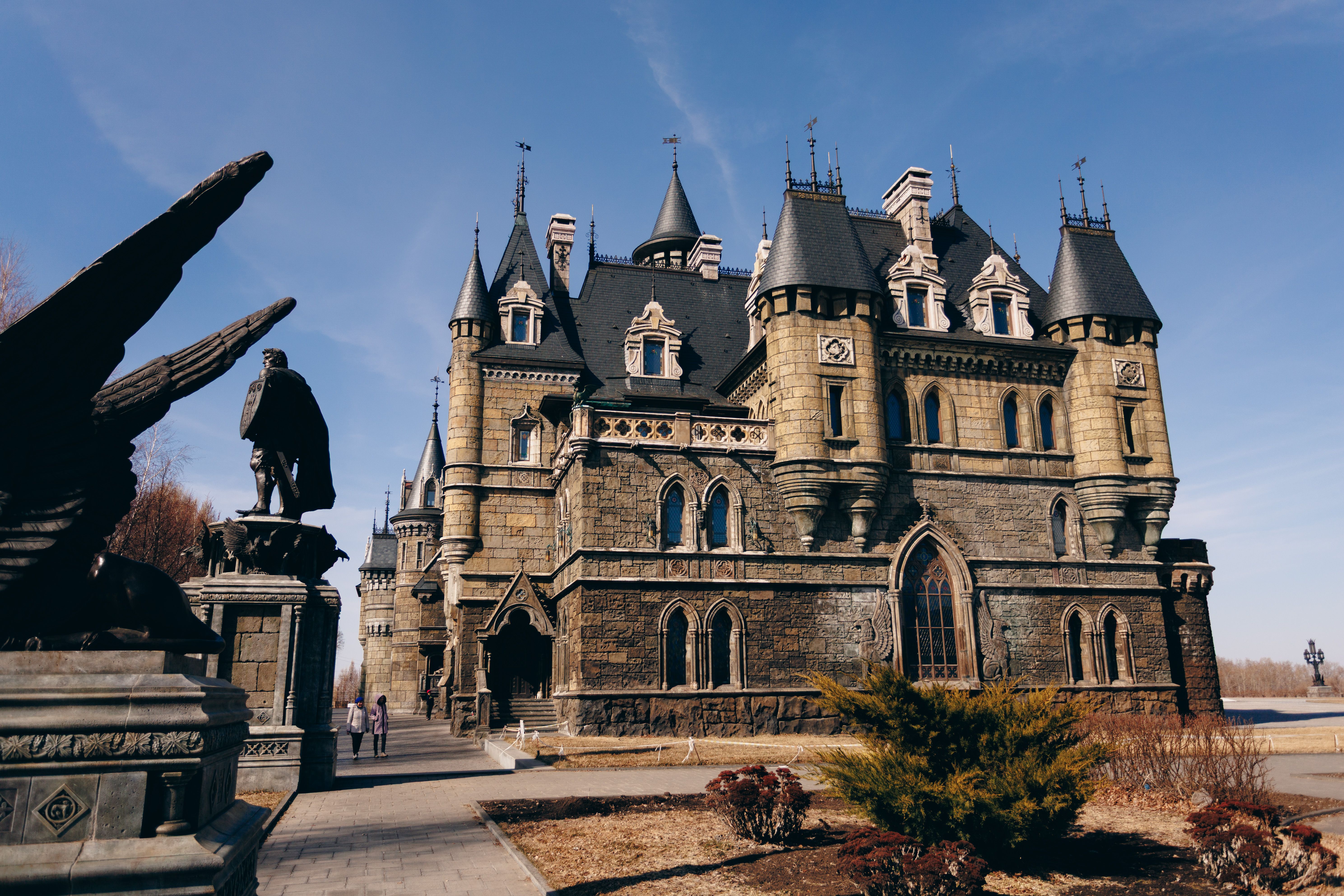Stunning Gothic-style castle with intricate architecture and statues under a bright blue sky.
