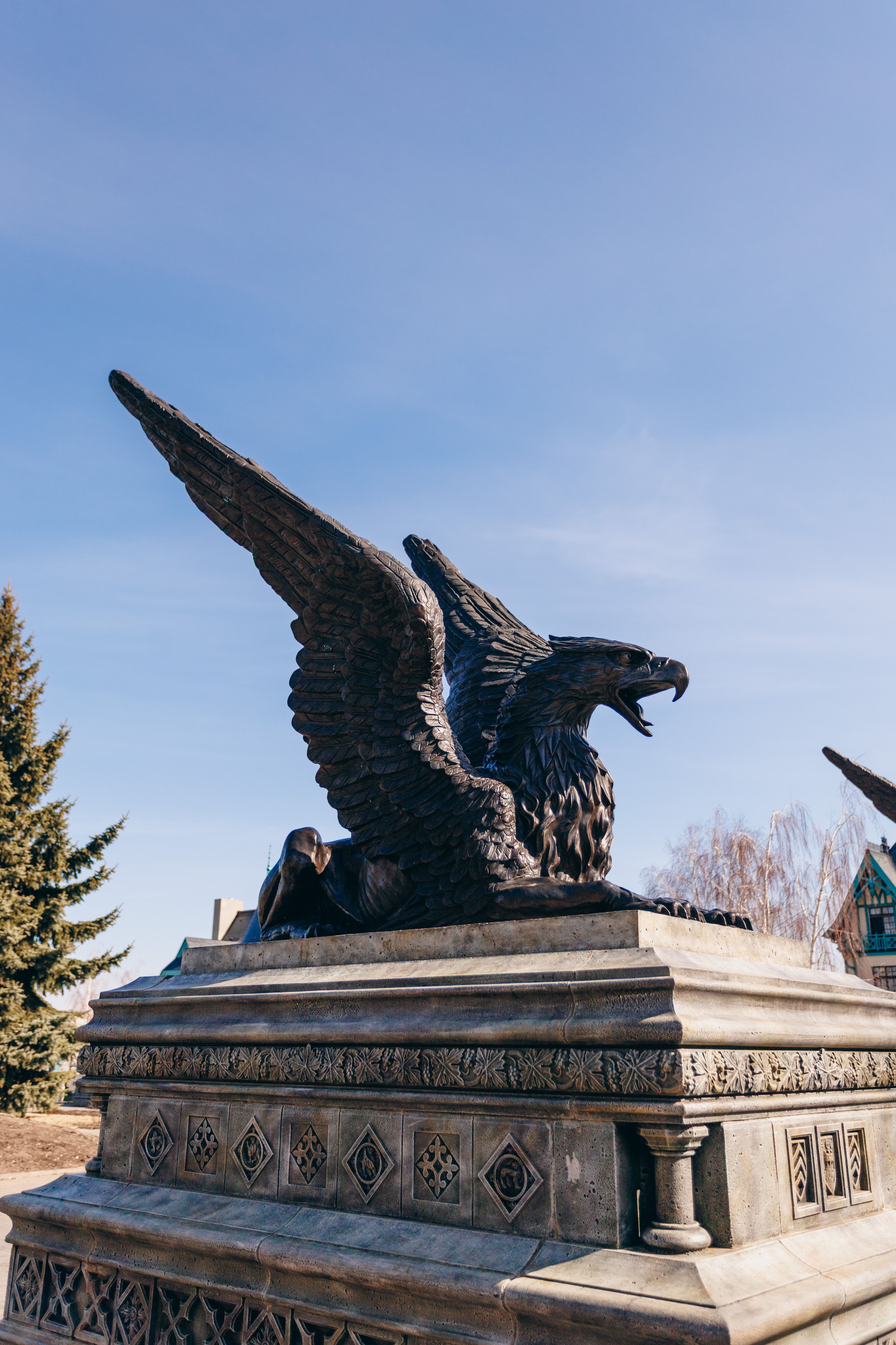 Impressive eagle statue on pedestal under clear blue sky, symbolizing freedom and power.