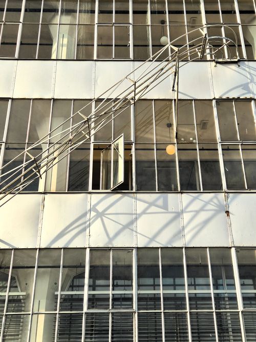 Free Perspective of a building facade with a fire escape and open window casting shadows. Stock Photo