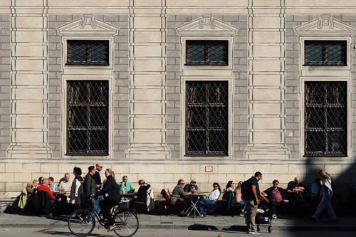 Free People enjoy sunny day outside cafe near historical building facade. Stock Photo