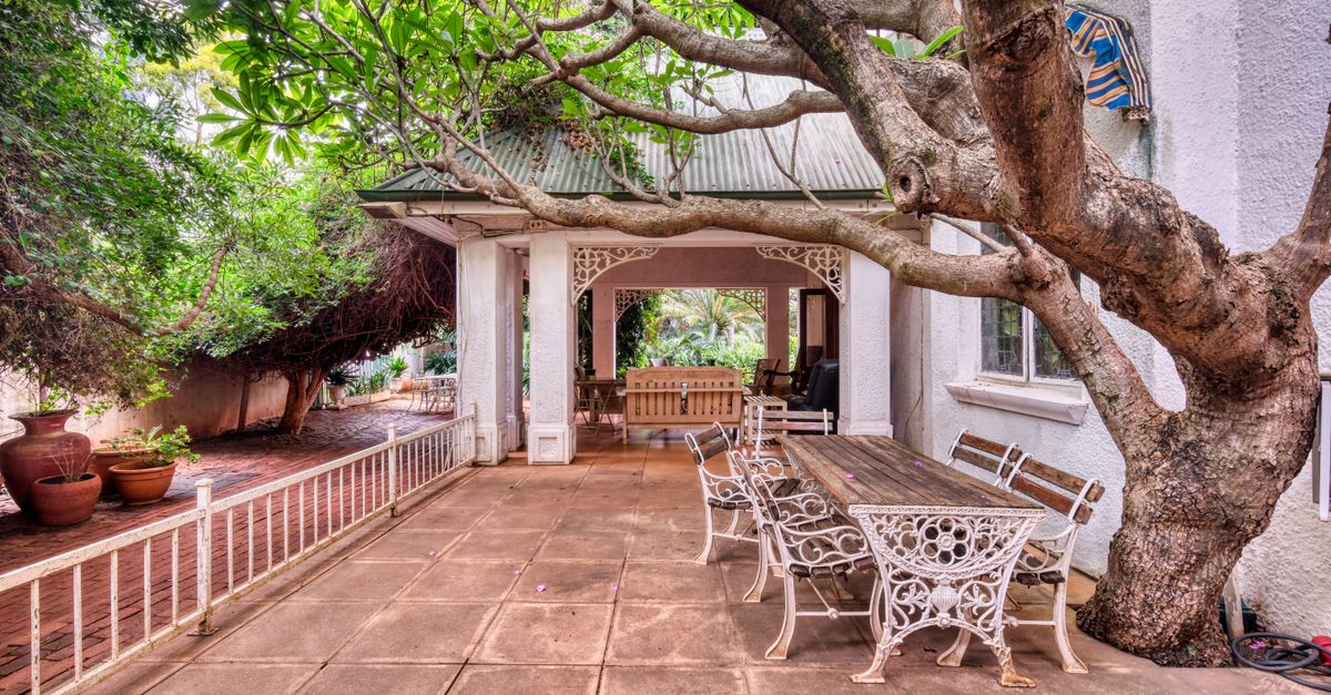 Rustic outdoor patio with vintage furniture and lush greenery, perfect for relaxation.
