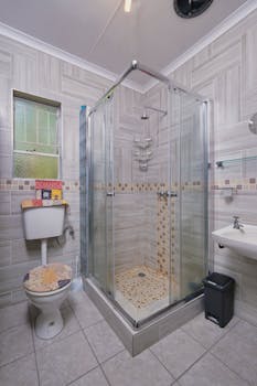 Contemporary bathroom featuring a sleek glass shower, tile flooring, and minimalistic decor.