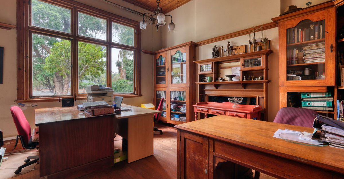 Warm and inviting traditional home office featuring vintage wooden furniture and large windows with garden view.
