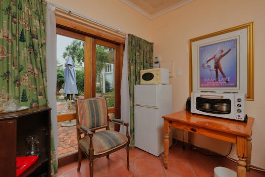 Charming kitchen area with garden access, fridge, microwave, and vintage decor.