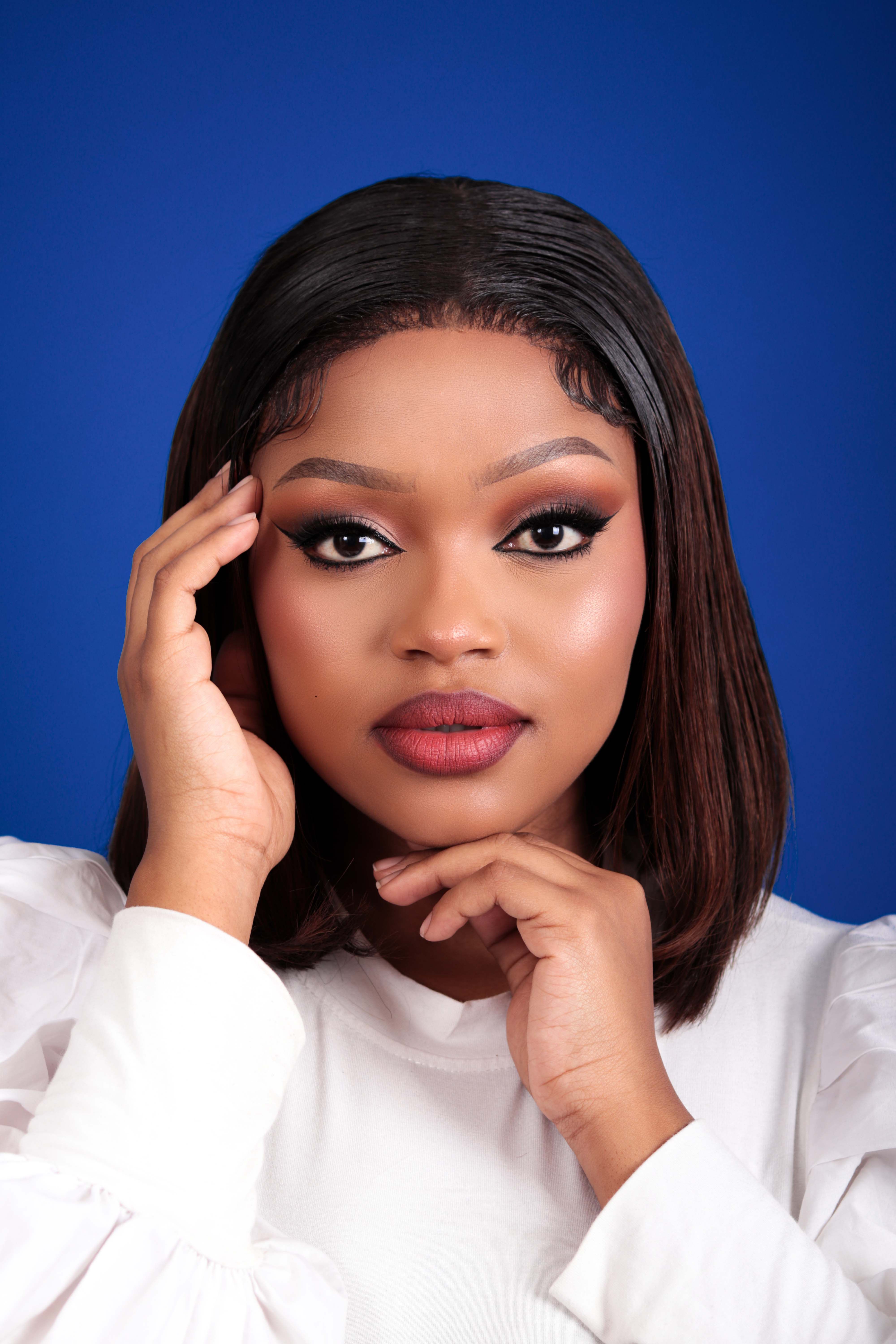 Stunning portrait of an adult woman with sophisticated makeup against a vivid blue background.