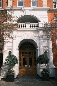 Front view of Albert Court's historic red brick entrance with white columns.