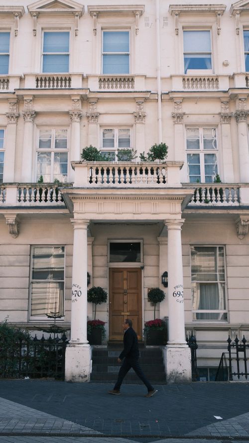 Free A historical Victorian townhouse facade with a person walking by in daylight. Stock Photo