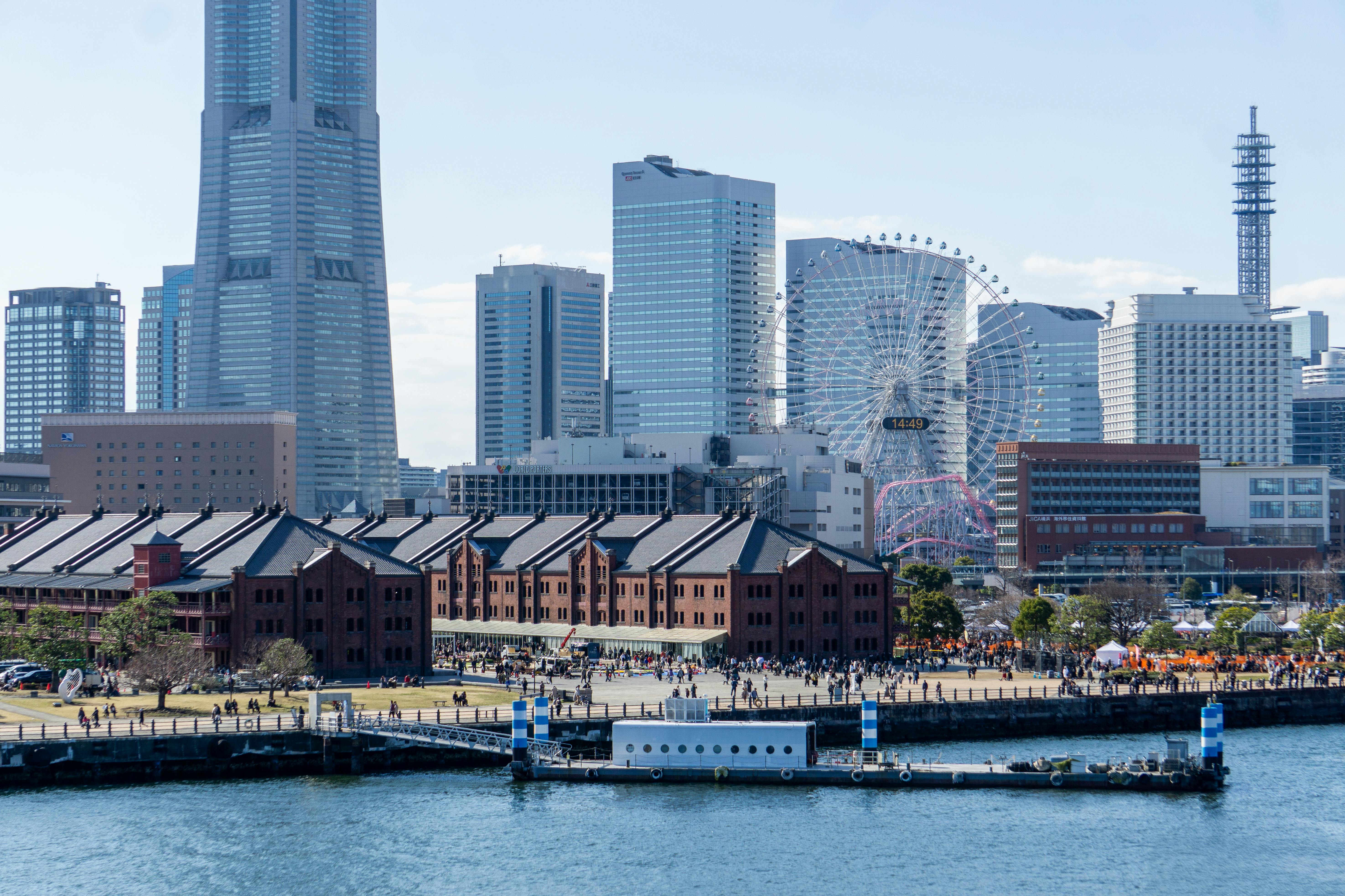 A vibrant cityscape of Yokohama featuring the Red Brick Warehouse, Ferris wheel, and modern skyscrapers.