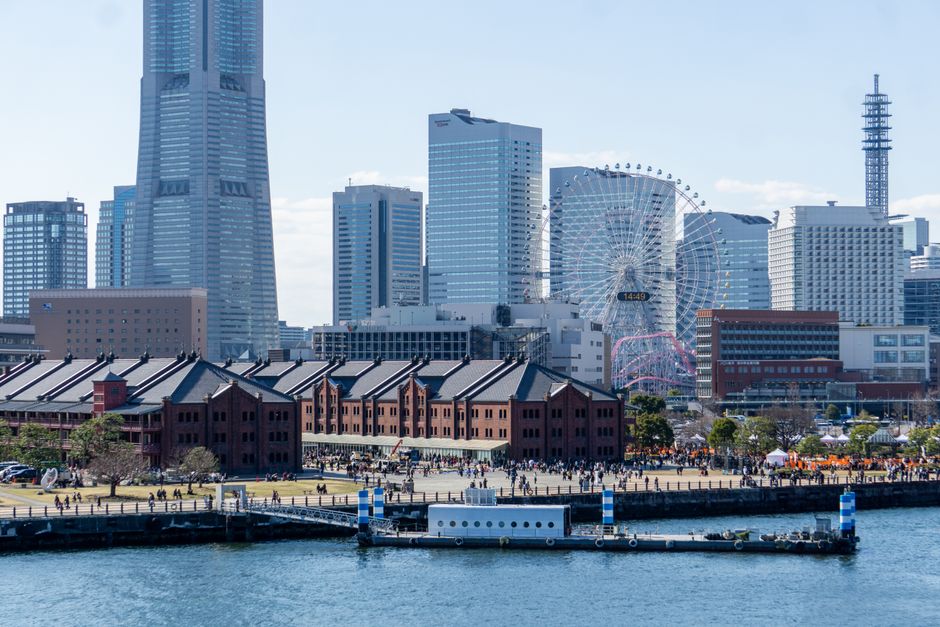 A vibrant cityscape of Yokohama featuring the Red Brick Warehouse, Ferris wheel, and modern skyscrapers.