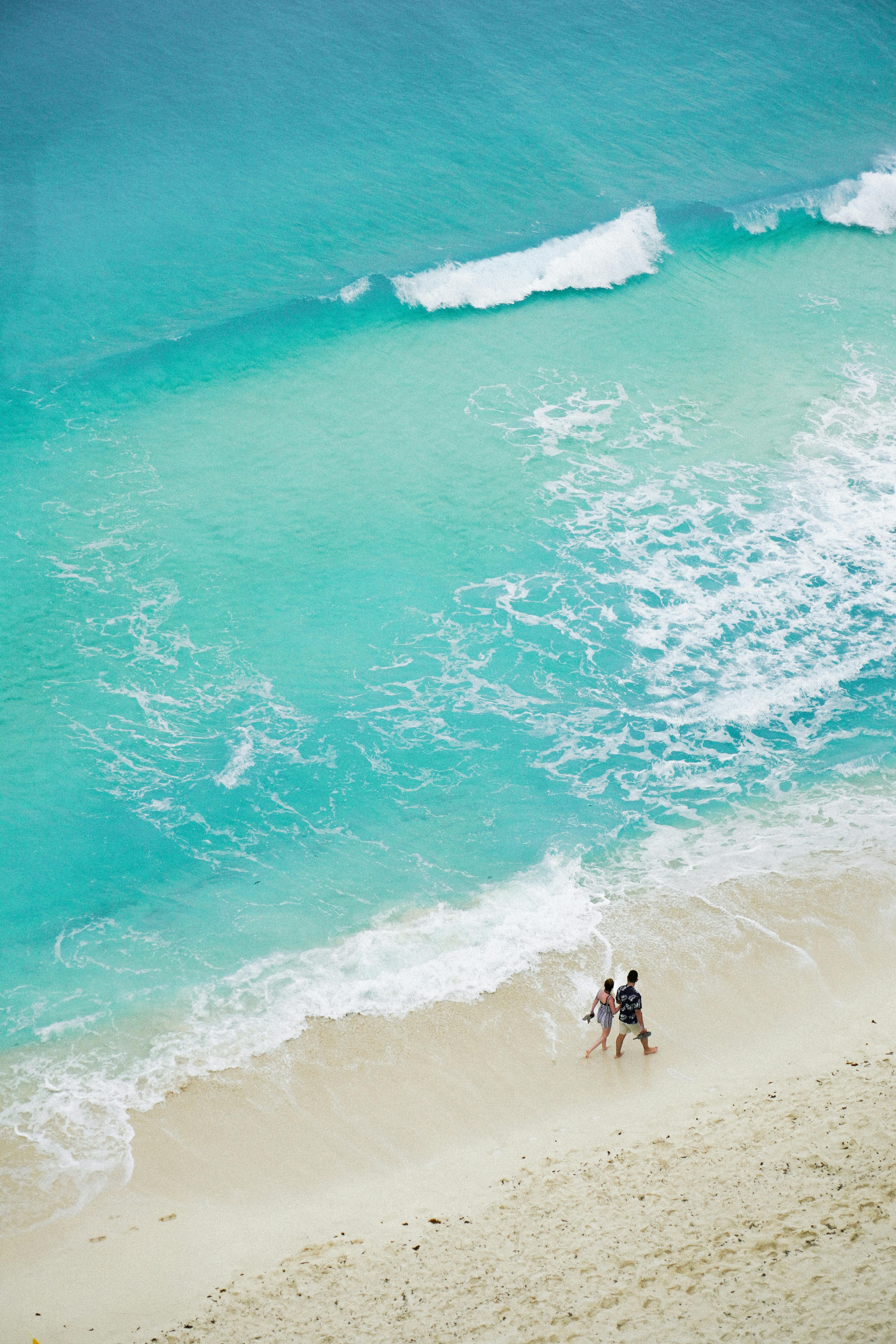 Couple strolling by turquoise waters on a sandy beach in Cancun.
