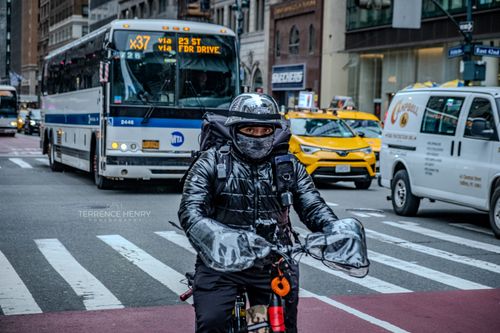 Free A bundled-up cyclist traverses the busy streets of New York City, surrounded by urban traffic. Stock Photo
