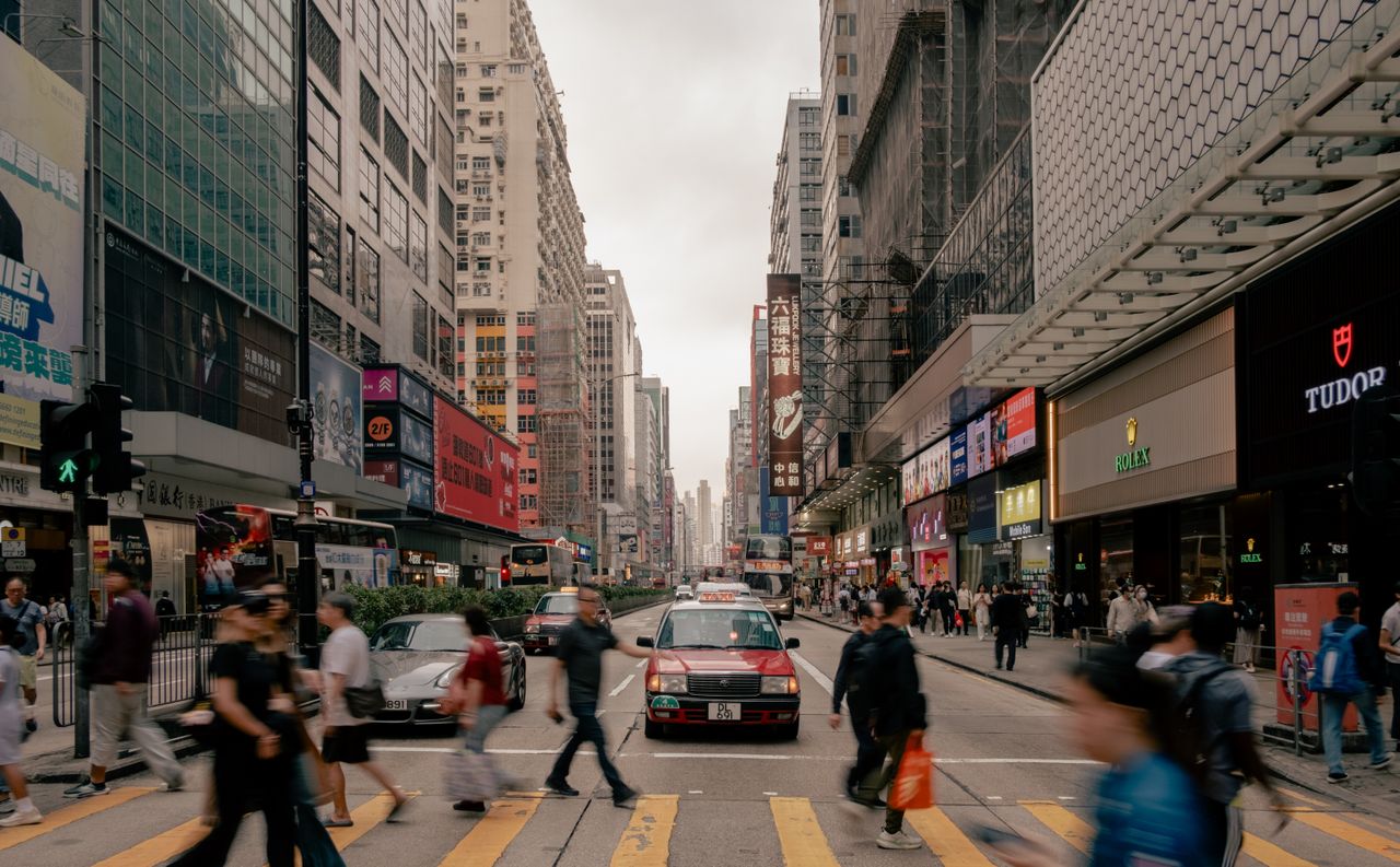 dynamic view of a busy hong kong street with pedestrians and taxis dur