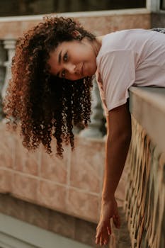 一张卷发女子在户外石栏杆上摆姿势的社论照片