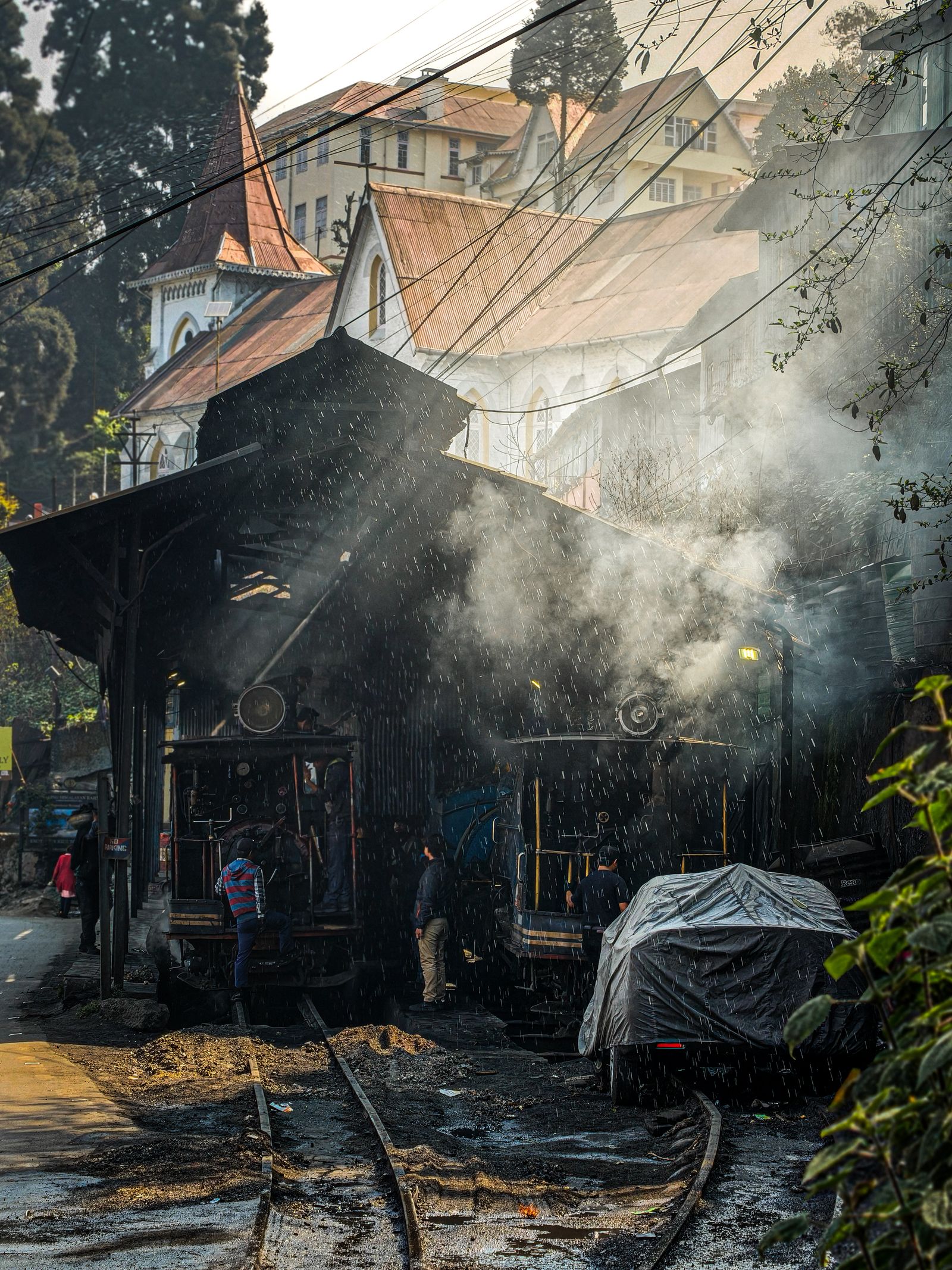 Steam and coal smoke rising around Darjeeling Himalayan Railway engines being readied at the station