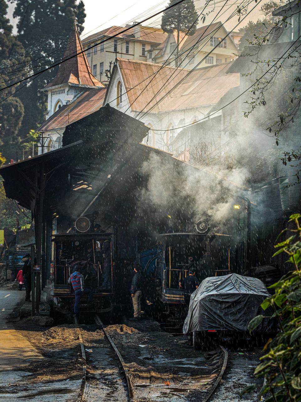 Steam and coal smoke rising around Darjeeling Himalayan Railway engines being readied at the station